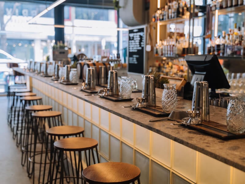 A fully stocked cocktail bar with empty stools in front of it